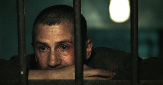 Man looking out through barred windows.