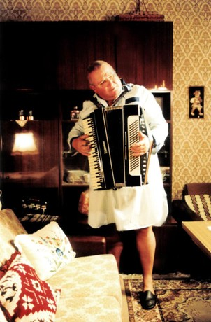 Schulze in his nightshirt, in his living room, playing the accordian