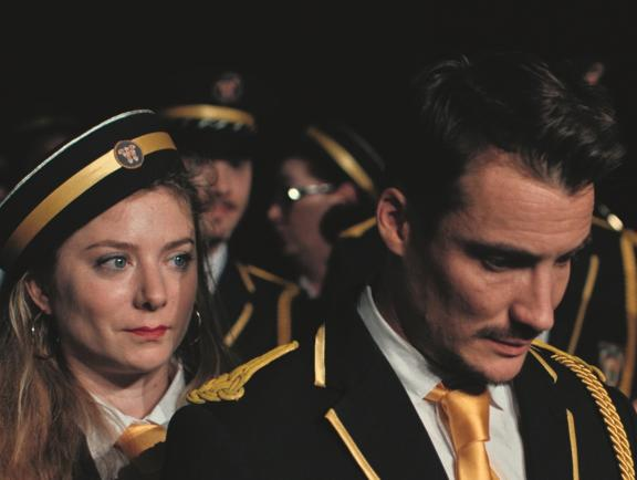 A woman with a concerned expression looking at man who is looking down.